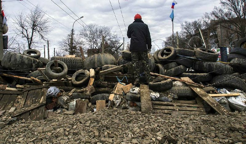 A man stands on a barricade Saturday at a Ukrainian regional security service office in Luhansk, about 20 miles west of the Russian border, as pro-Russian groups seized offices in Donetsk and Slovyansk in eastern Ukraine. 