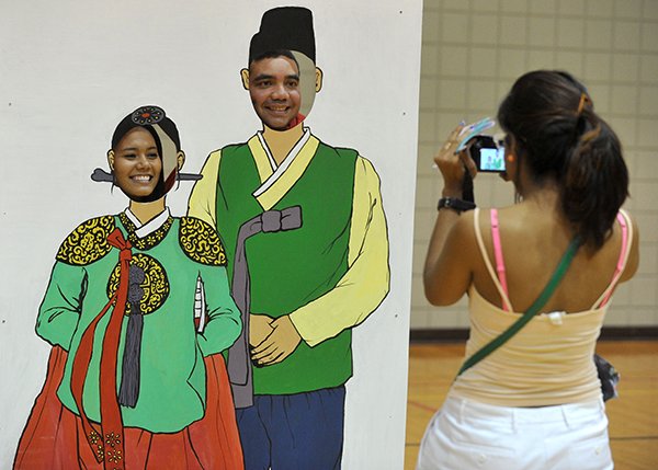Aniela Garay (right) snaps a photo of her friends Airam Morales (left) and Ubaldo Abrego — all from Panama City — during a Korean culture immersion event Saturday at the University of Arkansas in Fayetteville. 