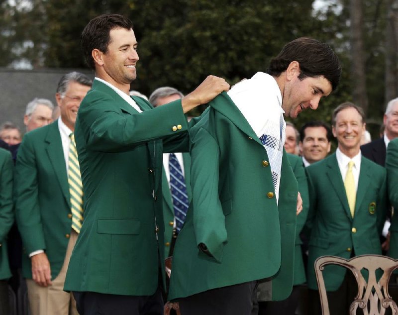 Defending Masters' champion Adam Scott, of Australia, helps Bubba Watson, right, with his green jacket after winning the Masters golf tournament Sunday, April 13, 2014, in Augusta, Ga. (AP Photo/Darron Cummings) 