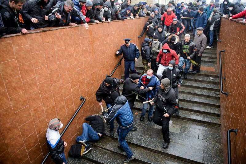 Pro-Russia supporters beat a pro-Western activist who lies on the stairs  during a pro Russian rally in Kharkiv, Ukraine, Sunday, April 13, 2014. Two rival rallies in Kharkiv turned violent after a group of pro-Russian protesters followed several pro-Ukrainian activists, beating them with baseball bats and sticks. (AP Photo/ Olga Ivashchenko)