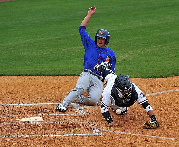 STAFF PHOTO MICHAEL WOODS 
• @NWAMICHAELW 
Juan Graterol of Northwest Arkansas dives after a throw from the outfield as Midland base runner Chad Oberakcer slides safely home to score a run in the second inning of Sunday’s game at Arvest Ballpark in Springdale.