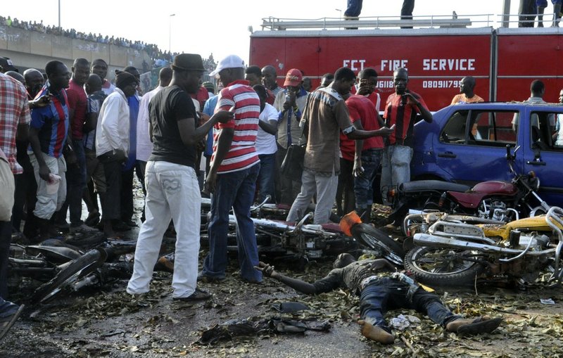 People gather at the site of a blast at the Nyanya Motor Park, about 16 kilometers (10 miles) from the center of Abuja, Nigeria, on Monday, April 14, 2014. An explosion blasted through a busy commuter bus station on the outskirts of Abuja early Monday as hundreds of people were traveling to work. 