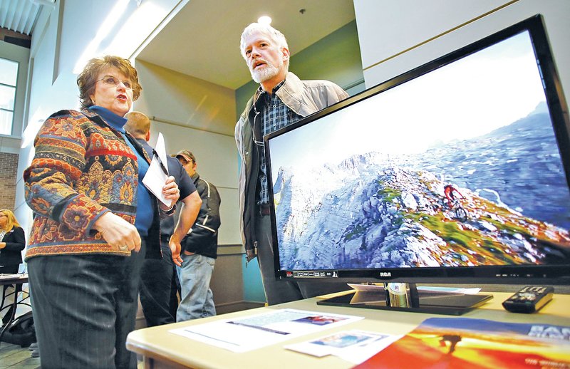 STAFF PHOTO DAVID GOTTSCHALK Marilyn Heifner, executive director of the Fayetteville Advertising and Promotion Commission, speaks Monday with Mike Schultz, with the Banff Mountain Film Festival World Tour in the Fayetteville Town Center. Sixteen event organizers and nonprofit groups met with and made their case for why their event should receive a portion of more than $225,000 in hotel, motel and restaurant tax money from the commission during a meet and greet event with the commissioners.