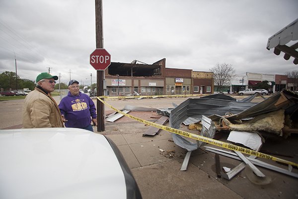Arkansas Democrat-Gazette/RYAN McGEENEY 
Lee Posey (left) and Charlie Wharton, both of Booneville, chat outside Crowley’s City Service, a small engine repair shop in Booneville, on Monday. High winds tore off the roof and part of the eastern-facing exterior wall of the Arkansas State Revenue Office building Sunday night, sending debris into the street and across the intersection into the window of the shop.