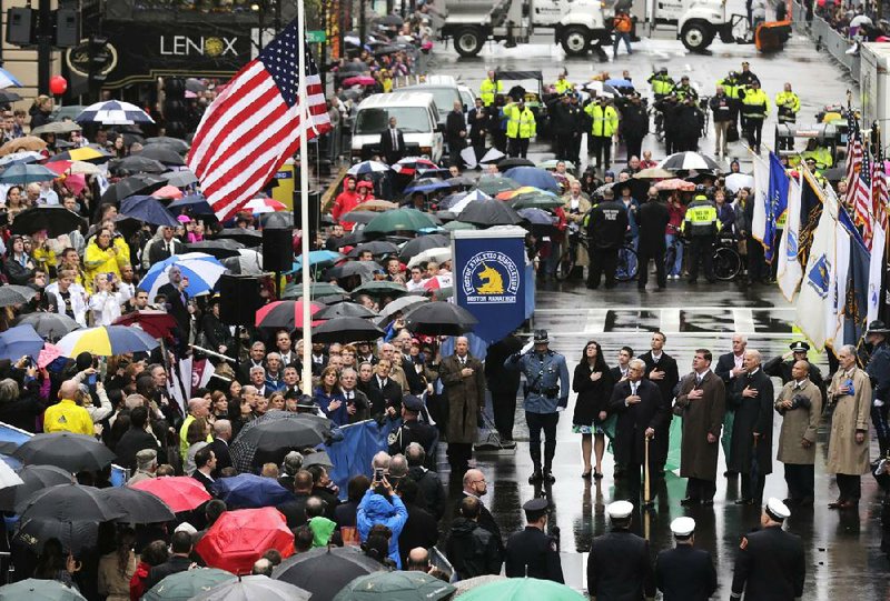 Survivors, first responders and others gather Tuesday as a flag is raised at the finish line of last year’s Boston Marathon a year after the bombings that left three people dead and more than 260 injured. 