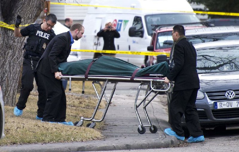 Police remove a body from a house where five people were fatally stabbed Tuesday at a party in northwest Calgary, Alberta. 