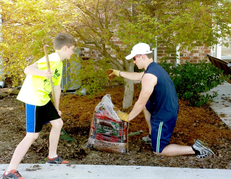 Submitted Photo Gravette High School senior, Joshua Lockhart, right, and Upper Elementary fifth grader, Connor LeBrecque, do their part for Earth Day, April 22, by raking out the leaves and re-mulching the beds in front of Glenn Duffy Elementary School. The boys are members of the Town & Country 4-H Club. The tree has special meaning to Lockhart as he and his grandfather, James Adams of Hiwasse, planted it when he was a kindergarten student at the school. He also shared a fact sheet about Earth Day with members at their recent 4-H meeting.