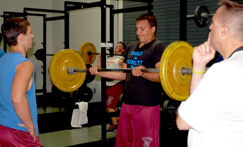 Graham Thomas/Herald-Leader Siloam Springs senior quarterback Chris Lampton, left, and head football coach Bryan Ross, right, look on as junior Aric Sislo does a curl lift during Monday&#8217;s offseason football workouts.