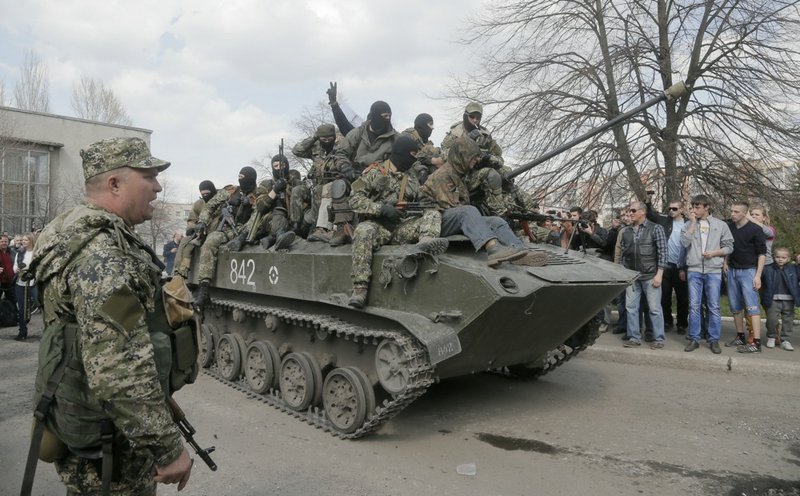 A combat vehicle with pro-Russian gunman on top goes through downtown Slovyansk on Wednesday, April 16, 2014. The troops on those vehicles wore green camouflage uniforms, had automatic weapons and grenade launchers and at least one had the St. George ribbon attached to his uniform, which has become a symbol of the pro-Russian insurgency in eastern Ukraine. 