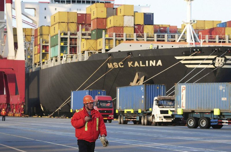 A dockworker passes a container ship in Qingdao port in east China last week. China’s government said Wednesday that the economy grew 7.4 percent from a year earlier in the January-March quarter. 