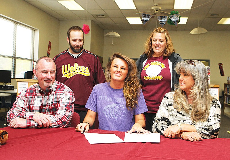 The Sentinel-Record/Richard Rasmussen BIRTHDAY GIFT: Lake Hamilton High senior Kori Bullard, seated center, smiles after signing a letter of intent on Wednesday, her 18th birthday, to play basketball and volleyball at Ouachita Baptist University. She is accompanied by parents Jim and Dana Bullard, seated left and right, and Lake Hamilton coaches Blake Condley, back left, and Karen Smith.