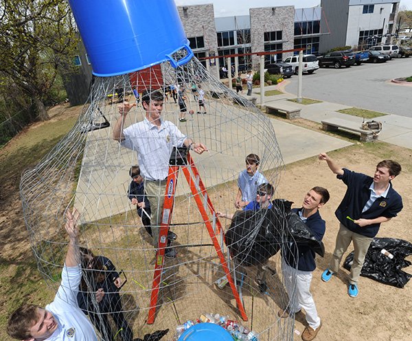 Haas Hall Academy seniors Hays Osborne, 19, top; Alex Walker, 18, right;  and Thomas Coger, 18, bottom; join other students in assembling a large bottle-shaped container constructed of wire Thursday, April 17, 2014, meant to collect recyclable plastic bottles at the school in Fayetteville. The school's green team is collecting bottles for a second year to raise awareness of the amount of bottles that are used but not recycled in advance of Earth Day, which is Tuesday.