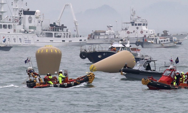 South Korean Navy officials work on buoys to mark the sunken passenger ferry, The Sewol, in the water off the southern coast near Jindo, South Korea, on Friday, April 18, 2014. 