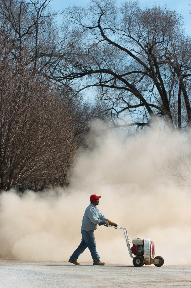 A groundskeeper blows the overnight pollen buildup off the 12th green Wednesday at Rebsamen Golf Course. 