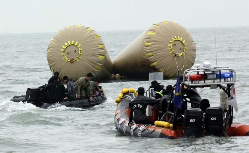 South Korean rescue members search passengers believed to have been trapped in the sunken ferry Sewol near the buoys which were installed to mark the area in the water off the southern coast near Jindo, south of Seoul, South Korea, Saturday, April 19, 2014. The captain of the sunken South Korean ferry was arrested Saturday on suspicion of negligence and abandoning people in need, as investigators looked into whether his evacuation order came too late to save lives. Two crew members were also arrested, a prosecutor said.