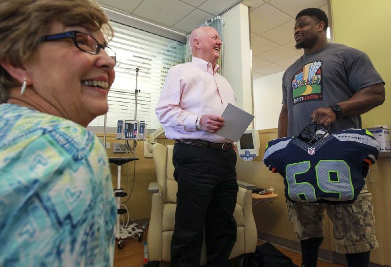 Former Seattle Seahawk and Jacksonville High School football player Clinton McDonald meets Ron Kirkland and his wife of Tuscumbia, Ala., during a visit with patients at the University of Arkansas for Medical Sciences Winthrop Rockefeller Cancer Institute in Little Rock on Friday. 