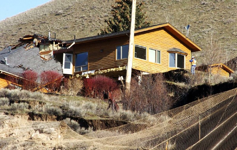 A worker inspects damage to a house Saturday at the top of a slow-moving landslide in Jackson, Wyo. 