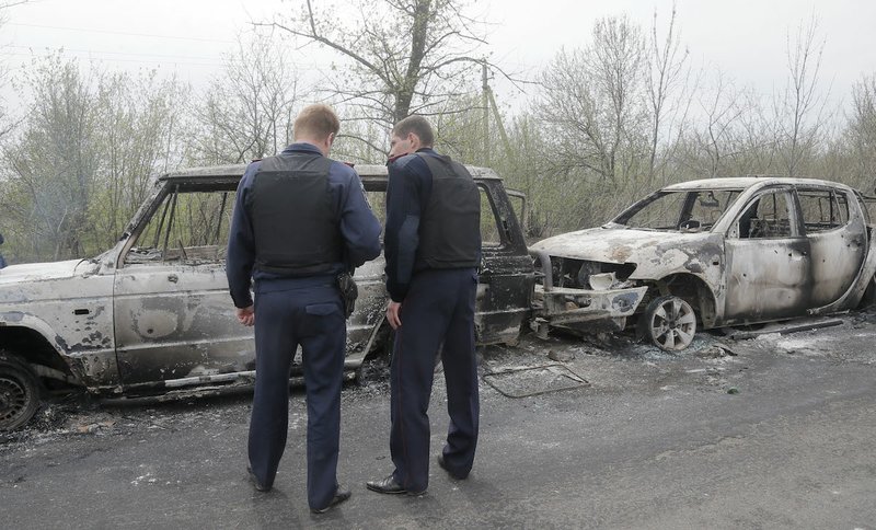 Local police officers inspect burnt-out cars after a night fight at the check point which is under the control of pro-Russian activists in the village of Bulbasika near Slovyansk, Ukraine, Sunday, April 20, 2014. At least one person was killed. Pro-Russian insurgents defiantly refused to surrender their weapons or give up government buildings in eastern Ukraine, despite a diplomatic accord reached in Geneva and overtures from the government in Kiev.