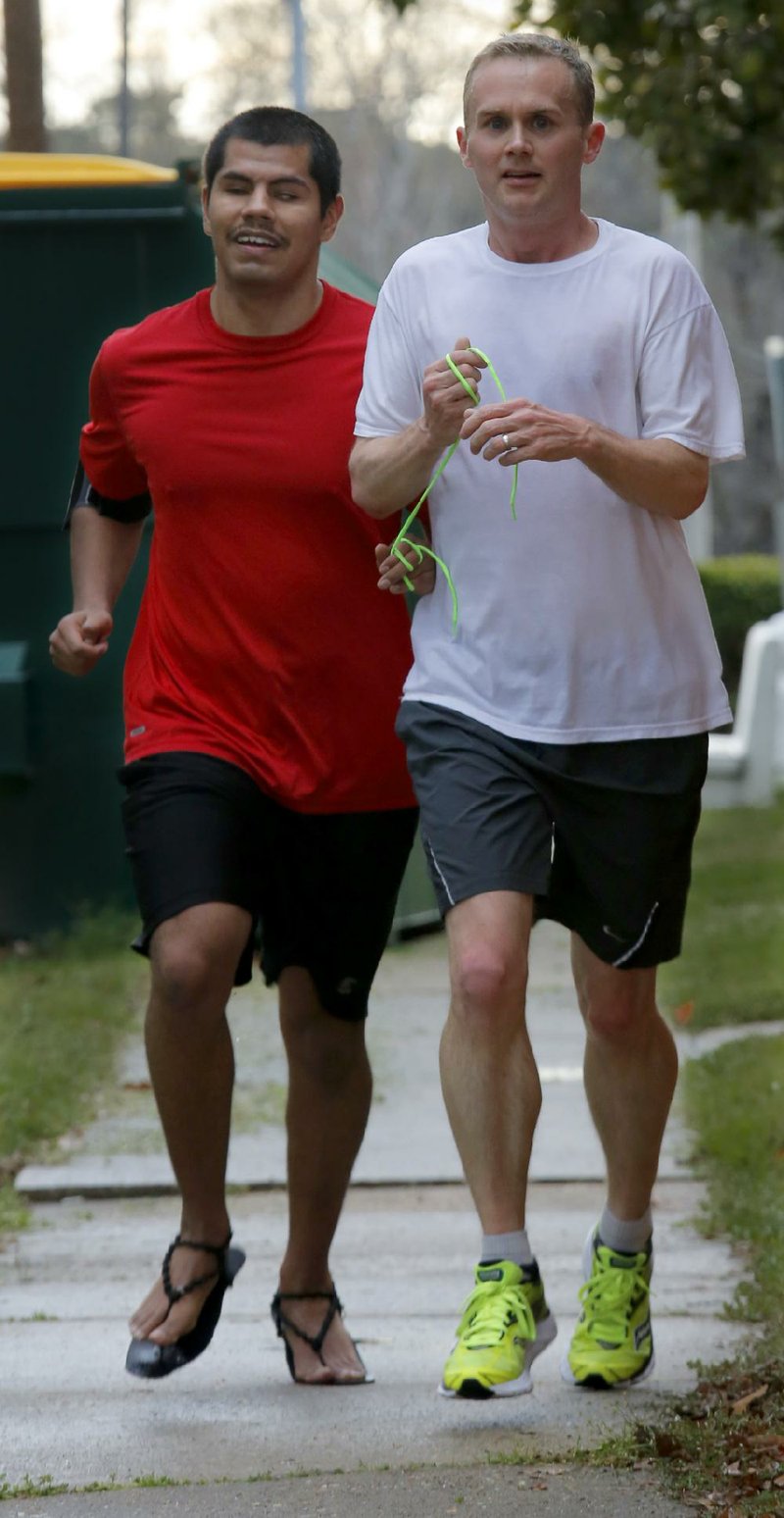 Arkansas Democrat-Gazette/JOHN SYKES JR. - Blind runner Gustavo Manzanales of Little Rock, (left) who is a rehabilitation counselor with Arkansas Department of Human Services and Chris Baldwin of Little Rock use a tether while running together. Baldwin was Manzanales' volunteer guide.