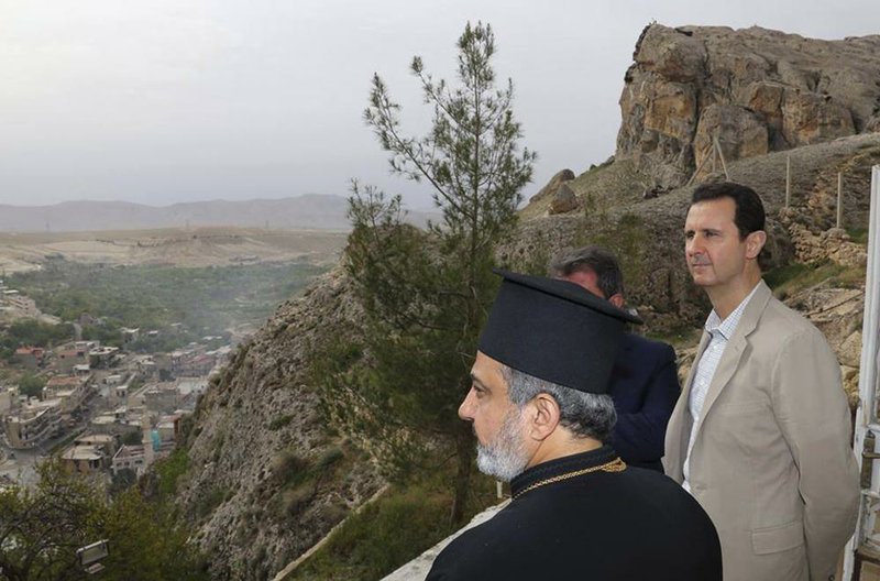 In this photo released by the Syrian official news agency SANA, Syrian President Bashar Assad, right, tours the Christian village of Maaloula, near Damascus, Syria, Sunday April, 20, 2014. Assad visited a historic Christian village his forces recently captured from rebels, state media said, as the country's Greek Orthodox Patriarch vowed that Christians in the war-ravaged country "will not submit and yield" to extremists. The rebels, including fighters from the al-Qaida-affiliated Nusra Front, took Maaloula several times late last year. (AP Photo/SANA)