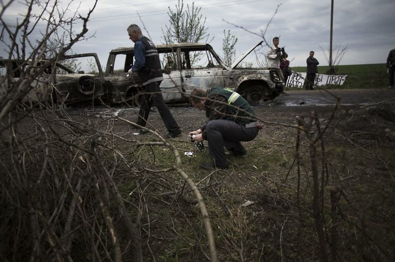 A Ukranian Police Officer takes pictures of evidence after a night fight at the check point, which was under the control of pro-Russian activists in the village of Bulbasika near Slovyansk, Ukraine, Sunday, April 20, 2014.(AP Photo/Manu Brabo)