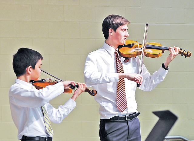 STAFF PHOTO BEN GOFF Erik Mains, left, 12, and his violin mentor Nicholas VanSlooten, 16, perform a duet Thursday during the Bentonville Public Schools Orchestra Mentorship Program solo/ensemble recital at Bright Field Middle School in Bentonville. Through the mentorship program, Bentonville High School orchestra students volunteer their time to teach weekly music lessons to students from all four Bentonville middle schools.