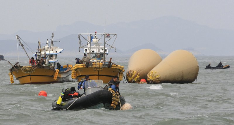 South Korean rescue team members work to rescue passengers believed to have been trapped in the sunken ferry Sewol near the buoys which were installed to mark the vessel in the water off the southern coast near Jindo, South Korea, on Monday, April 21, 2014. 