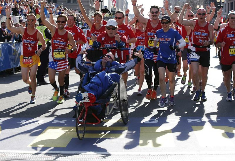 Dick Hoyt and Rick Hoyt, from Holland, Mass., cross the finish line surrounded by supporters in the 118th Boston Marathon, Monday, April 21, 2014 in Boston. The Hoyts have said this, their 32nd Boston Marathon, will be their last. (AP Photo/Elise Amendola)