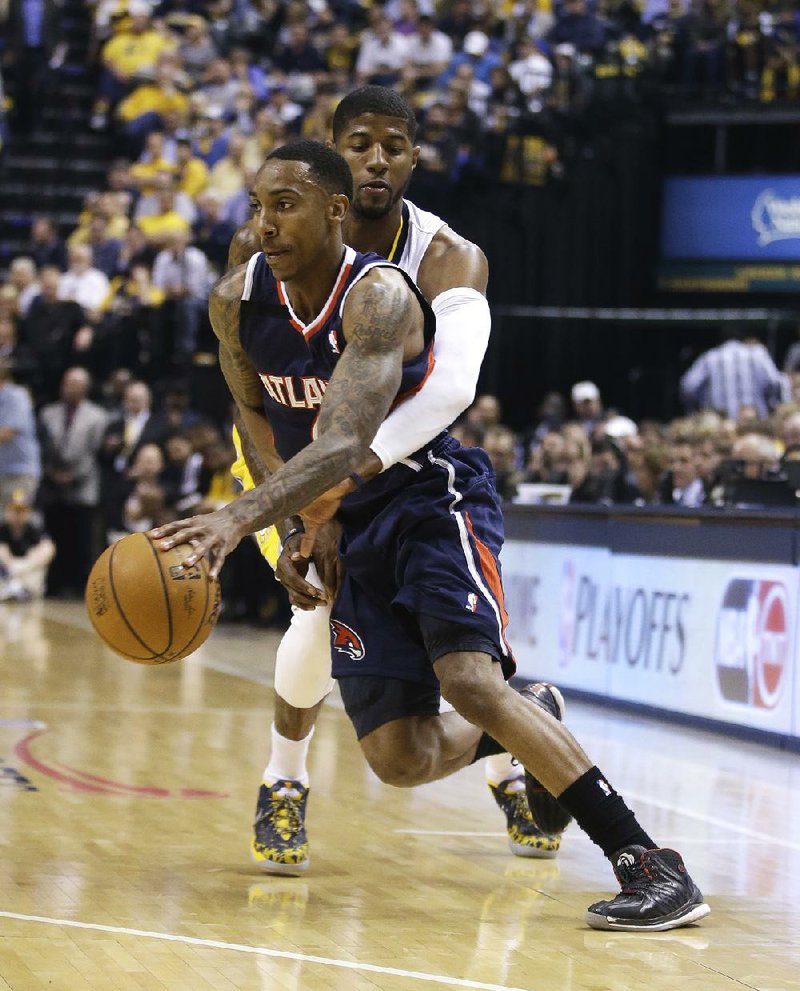 Paul George (back) of the Indiana Pacers tries to knock the ball away from Jeff Teague of the Atlanta Hawks during Tuesday night’s NBA playoff game in Indianapolis. 