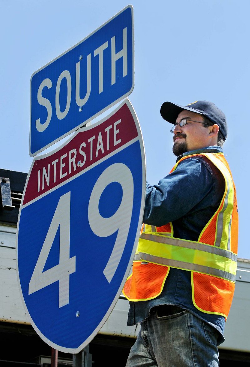 STAFF PHOTO BEN GOFF 
Jake Trotter, with the Arkansas Highway and Transportation Department, changes a U.S. 71 sign to a new Interstate 49 sign near Exit 93 in Bentonville on Tuesday. 