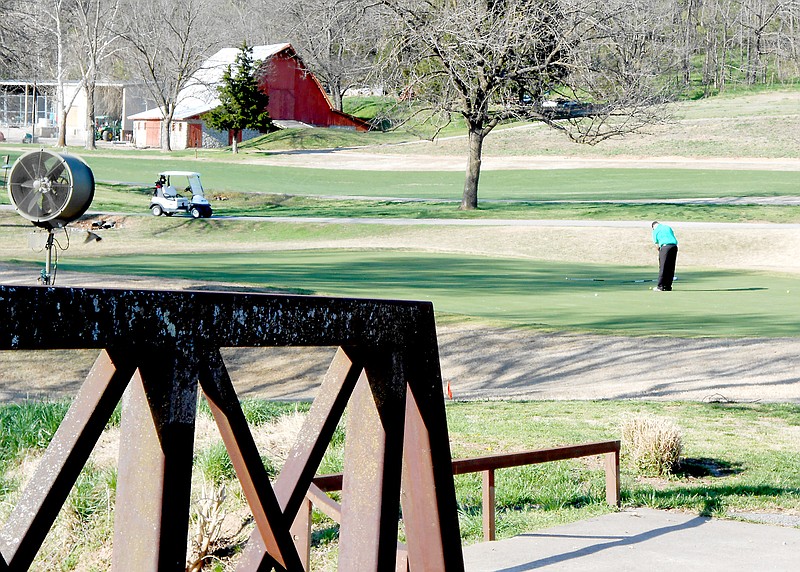 Courtesy of Xyta Lucas A lone golfer practices his putting on the No. 3 green with the golf cart bridge in the foreground and the old barn, believed to have been built in 1903, visible in the distance.