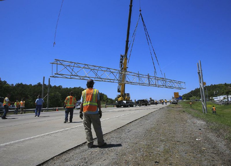 Arkansas Highway and Transportation Department workers lower an overhead sign structure to the ground Wednesday afternoon in the westbound lanes of Interstate 40 near Crystal Hill Road after a dump truck with a raised bed struck it, causing traffic backups for much of the day on the busy roadway. The crash was the second in a week involving a dump truck on I-40.