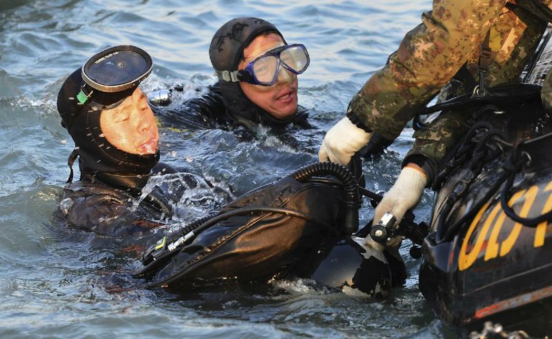 Divers searching the sunken ferry Sewol surface Wednesday off the southern coast of South Korea. Officials said divers now have to rip through walls to recover bodies. 