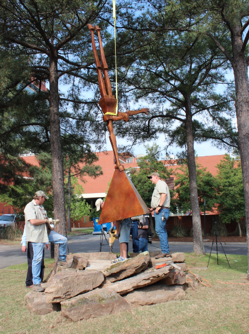 Crews work to install "Cecil," a new sculpture of a man doing a one-armed handstand, Thursday at Riverfront Park in Little Rock.