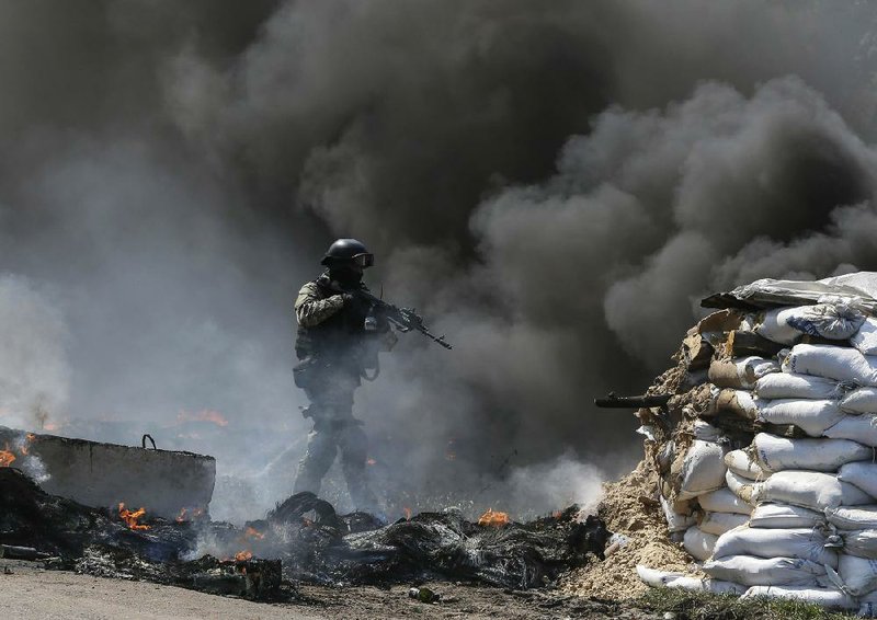 A member of Ukraine’s security forces faces smoke and fire during clashes Thursday with pro-Russia militiamen. The Ukrainian government moved Thursday to oust insurgents from government buildings in the east. 