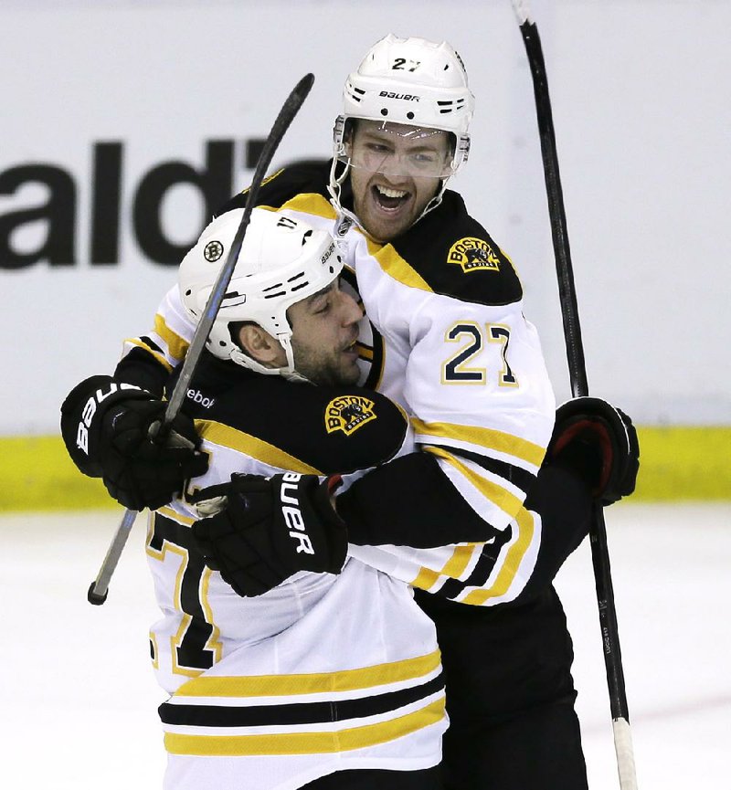 Boston Bruins defenseman Dougie Hamilton (27) and left wing Milan Lucic (17) celebrate the Bruins' 3-2 overtime win against the Detroit Red Wings in Game 4 of a first-round NHL hockey playoff series in Detroit, Thursday, April 24, 2014. Jarome Iginla was credited with the goal with an assist by Hamilton. (AP Photo/Carlos Osorio)