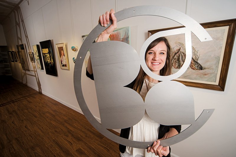 The Batesville Area Arts Council has moved to a new space on Main Street and has a new director, Paige Dirksen, above, who holds an aluminum version of the Batesville Arts Council  logo that will hang in the gallery.