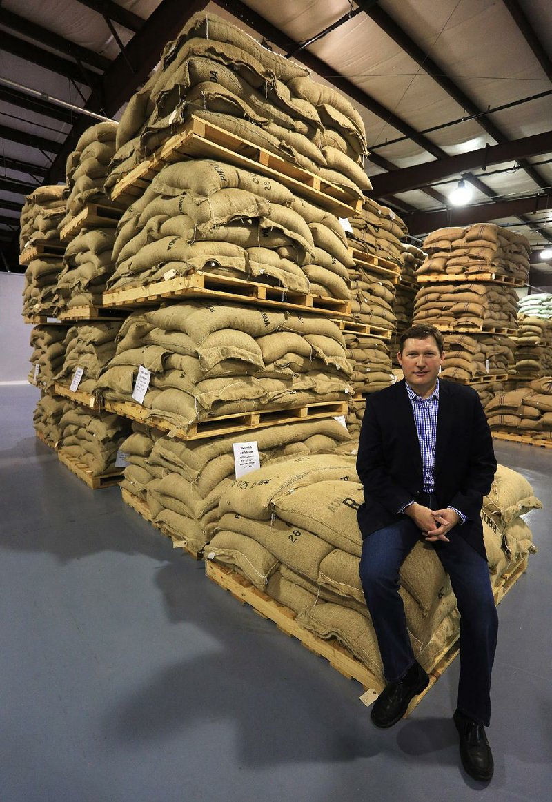 Todd Brogdon, chief executive officer of Westrock Coffee Co., sits on a bag of coffee beans from Rwanda at the company’s warehouse in Maumelle. The company began importing Rwandan coffee beans in 2009. 