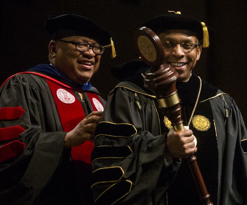 University of Arkansas at Pine Bluff Chancellor Laurence Alexander (right) receives the chancellor’s mace Friday from UA Trustee Stephen Broughton at Alexander’s investiture ceremony at the Pine Bluff Convention Center. 