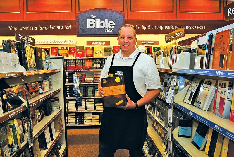 STAFF PHOTO FLIP PUTTHOFF Keith Newton, manager at LifeWay Christian Store in Rogers, stands among several types and translations of Bibles available at the store at Pinnacle Hills Promenade.