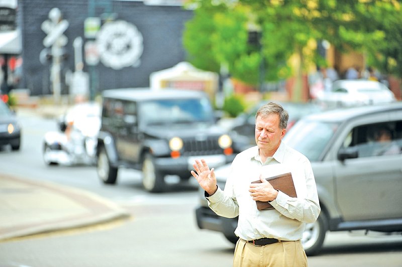 File Photo William Collins of Fayetteville prays May 3, 2012, as traffic passes along West Dickson Street during the local observance of the National Day of Prayer. This year&#8217;s observances will take place Thursday throughout the region.