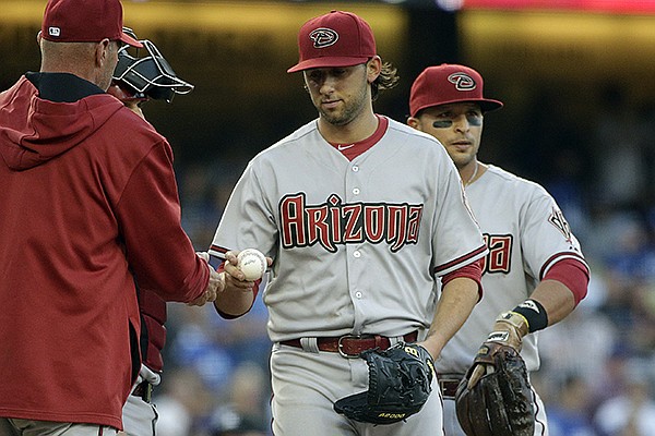 Arizona Diamondbacks starting pitcher Mike Bolsinger, center, hands the ball to manager Kirk Gibson, left, during the fifth inning of a baseball game against the Los Angeles Dodgers, Saturday, April 19, 2014, in Los Angeles. (AP Photo/Jae C. Hong)