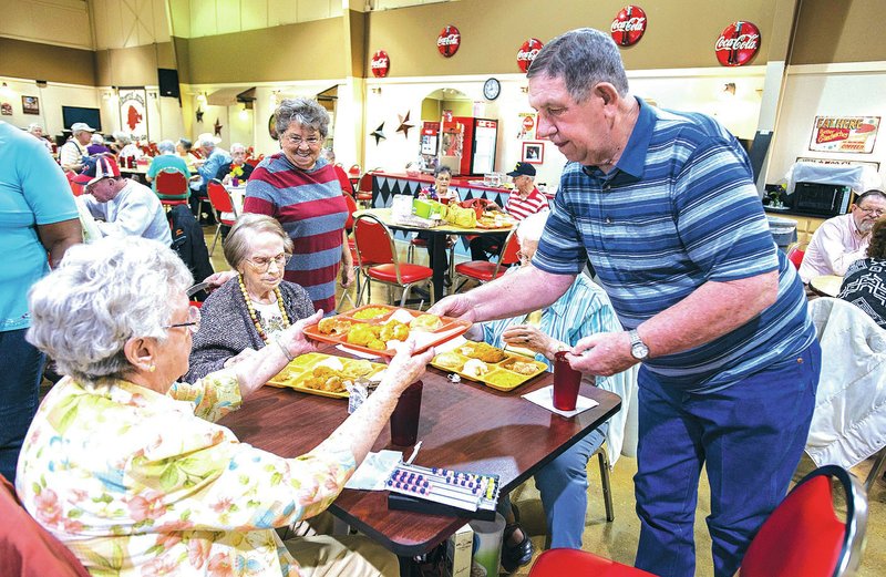 STAFF PHOTO ANTHONY REYES Bobby Johnson of Springdale gives a lunch tray to Edith Seiter on Friday at the Springdale Senior Center. Johnson has been a volunteer at the center for several years and Seiter said she eats lunch at the center three or four times a week.