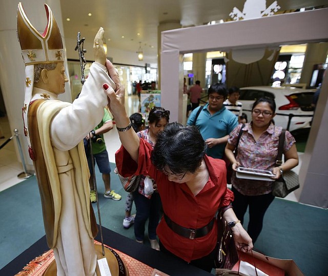 A devotee touches to pray at the statue of Roman Catholic Pope John Paul II on display with other relics of the late Pope as well as Pope John XXIII in celebration of their canonization or the elevation to sainthood Sunday, April 27, 2014, at suburban Quezon city, northeast of Manila, Philippines. Pope Francis declared his two predecessors John XXIII and John Paul II saints on Sunday before hundreds of thousands of people in St. Peter's Square, an unprecedented ceremony made even more historic by the presence of retired Pope Benedict XVI. The predominantly Roman Catholic Philippines joins several nations worldwide in the celebration of canonization of the two Popes. (AP Photo/Bullit Marquez)