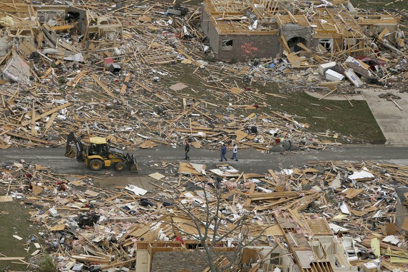 People walk between two destroyed houses in Mayflower on Monday, April 28, 2014, after a tornado struck the town late Sunday. 