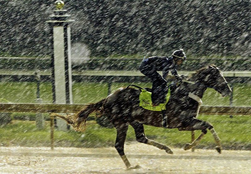 Exercise rider Abel Flores takes Kentucky Derby hopeful Tapiture for a morning workout in the rain at Churchill Downs Monday, April 28, 2014, in Louisville, Ky. (AP Photo/Garry Jones)