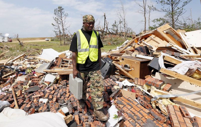 Deramus Idon looks Tuesday at the remains of a house in which he and nine others hid Monday as a tornado hit his neighborhood in south Louisville, Miss. Numerous businesses, residences and the community hospital were destroyed or heavily damaged after a tornado hit the east Mississippi community. 