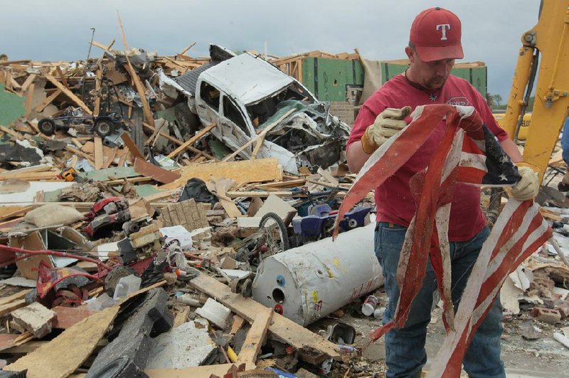 Gary Moore (top photo) finds a tattered flag Tuesday while searching through the rubble of his home in the Parkwood Meadows neighborhood of Vilonia. 