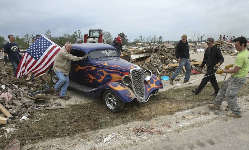 Friends and volunteers help get Dan Wasson’s 1934 Ford out of the rubble Tuesday in Vilonia. 