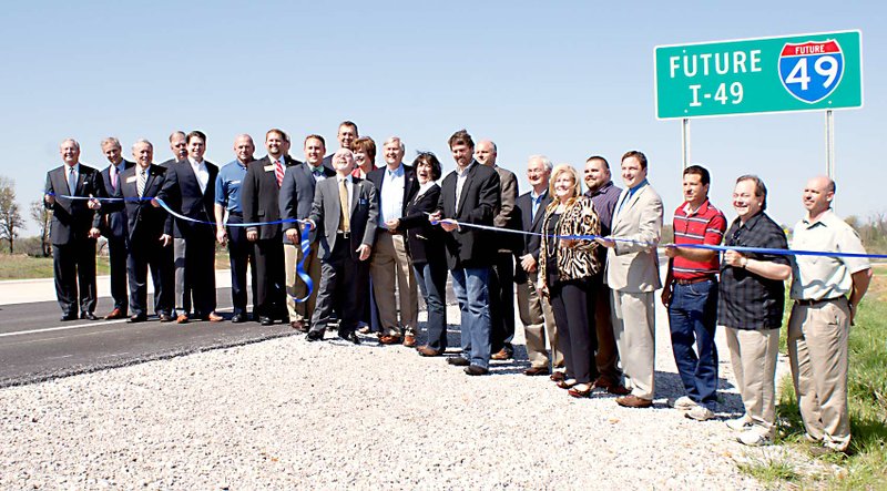 Photo by Dodie Evans State and local dignitaries lined up as Scott Bennett, director of the Arkansas Highway and Transportation Dept., cuts the ribbon officially opening the first leg of the Bella Vista Bypass.